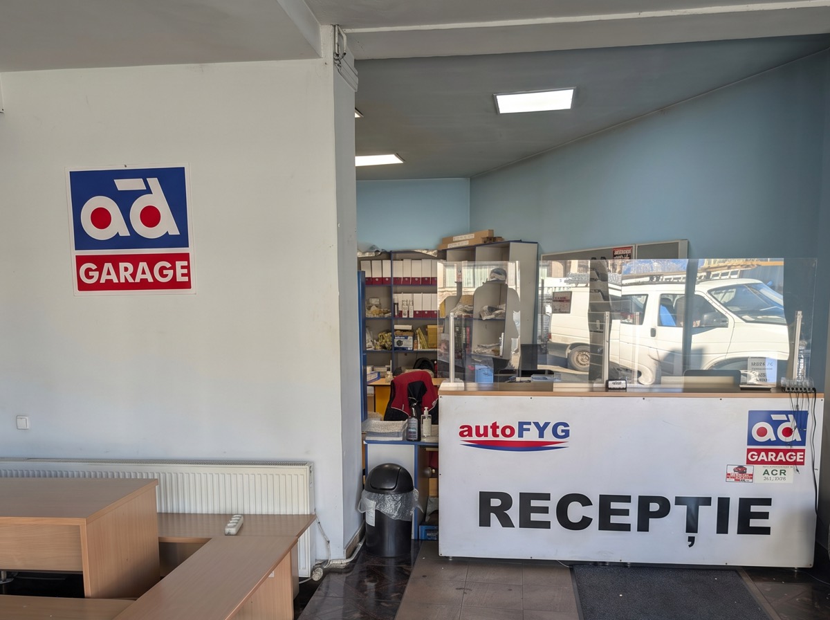 Recepția autoFYG: tejghea albă cu sigla autoFYG și inscripția RECEPȚIE, lângă sigla AD Garage